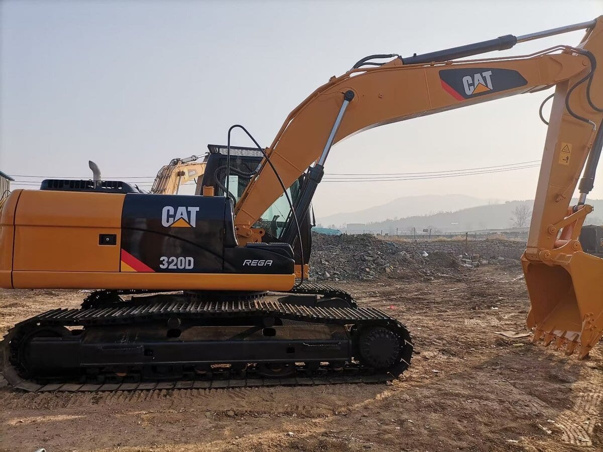 Compact yellow Caterpillar excavator working on a construction site, featuring the CAT logo and model number 320D, optimized for earthmoving and demolition tasks.