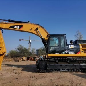 Excavator, yellow and black CAT 336D2L model, working on construction site with blue sky overhead, detailed view of hydraulic arm and tracked undercarriage.